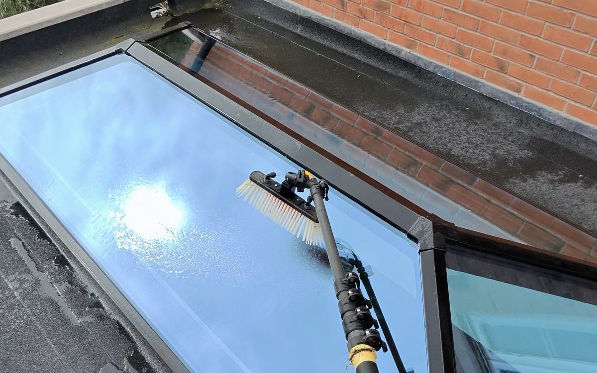 Josh cleaning the glass of a lantern roof light with a water fed pole and pure water