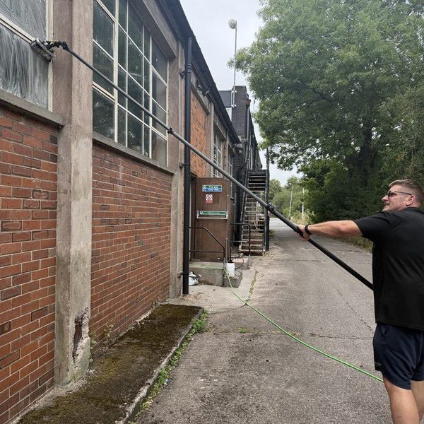 Cleaning the windows of an industrial unit from the ground with a water fed pole