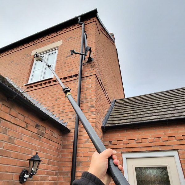 A water fed pole reaching a first floor window on the side of a detached house