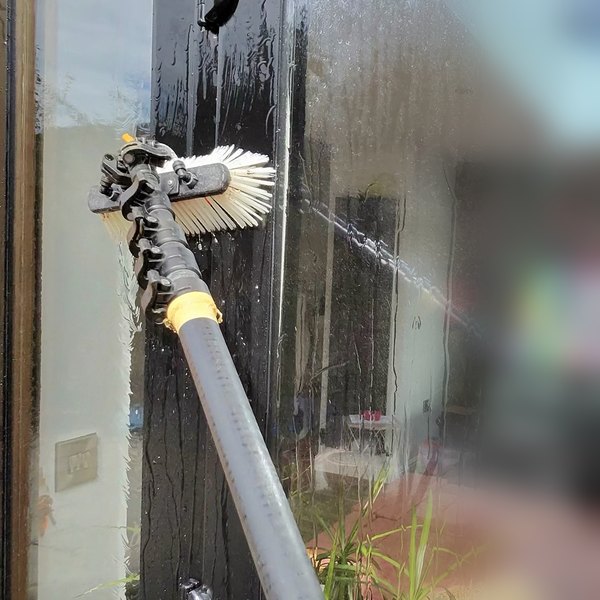 Cleaning the glass in a patio door with a brush and pure water